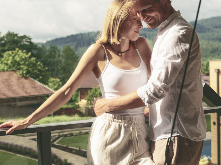 Ein glückliches Paar auf dem Balkon eines Tonihof-Appartments mit herrlichem Ausblick auf die umliegende Landschaft.