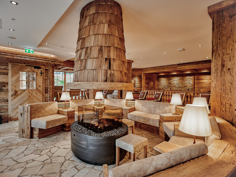 Gemütlicher Ruhebereich des Tonihof mit komfortablen Sesseln und Sofas zum entspannen, stimmungsvoll ergänzt durch einen Kamin.